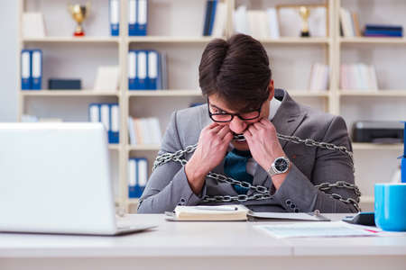 Businessman tied with chains to his workの写真素材