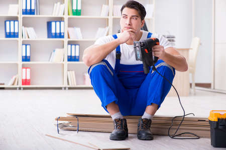 Young worker working on floor laminate tilesの写真素材