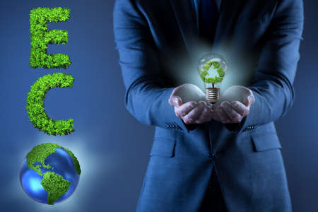 Businessman holding lamp in green environment conceptの写真素材