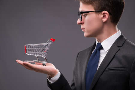 Businessman with shopping cart on gray backgroundの写真素材