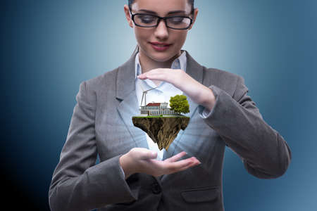 Businesswoman holding flying island in eco conceptの写真素材