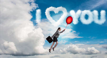 Woman flying balloons in romantic conceptの写真素材