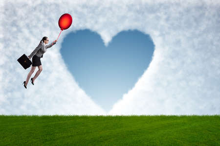 Woman flying balloons in romantic conceptの写真素材
