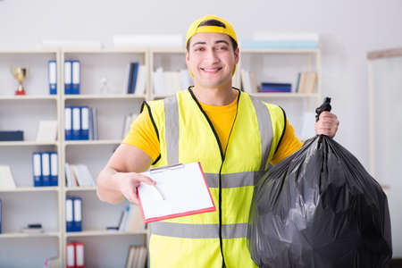 Man cleaning the office and holding garbage bagの写真素材