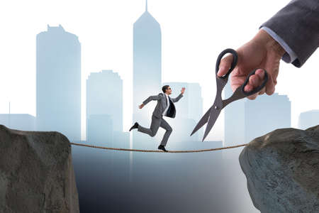 Hand cutting the rope under businessman tightrope walker