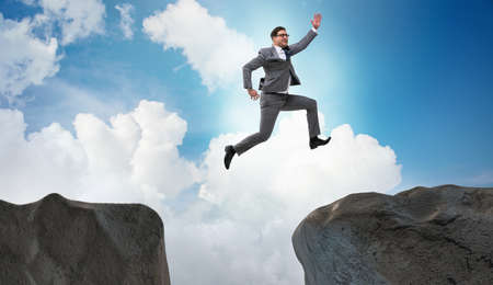 Ambitious businessman jumping over the cliffの写真素材