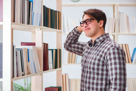 Young student looking for books in college libraryの写真素材