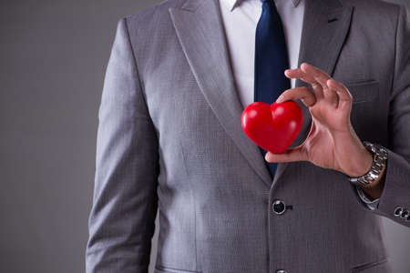Businessman holding red heart in love concept