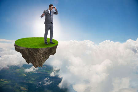 Businessman on flying island with binocularsの写真素材