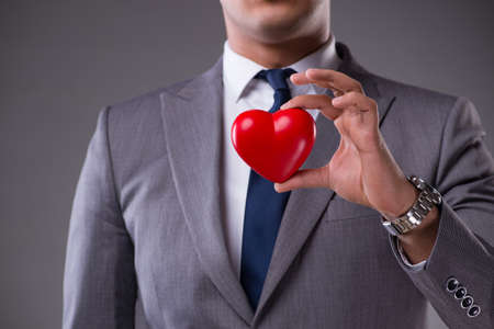Businessman holding red heart in love conceptの写真素材