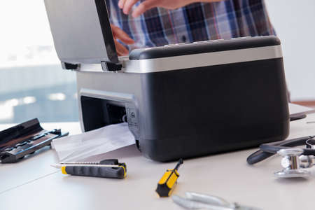 Repairman repairing broken color printerの写真素材