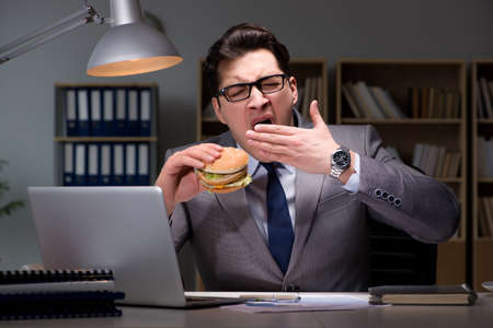 Businessman late at night eating a burgerの写真素材