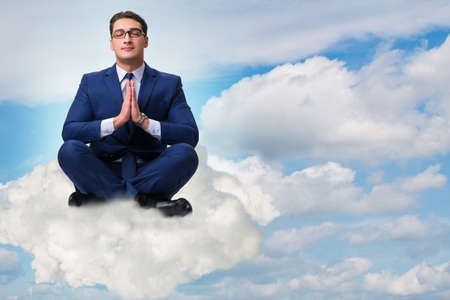 Businessman meditating in the skyの写真素材