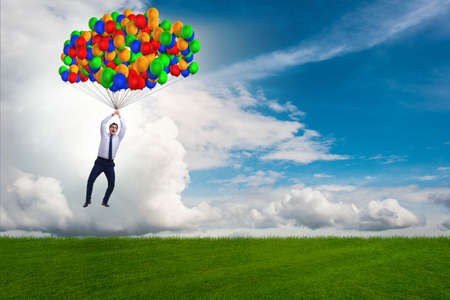 Businessman flying balloons on bright dayの写真素材
