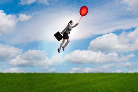 Businesswoman flying balloons on bright day