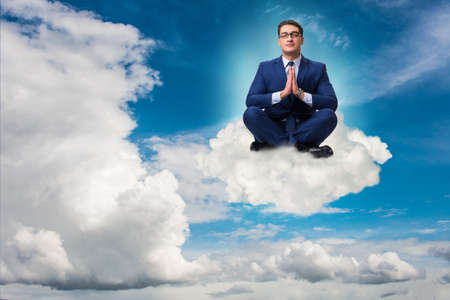 Businessman meditating in the skyの写真素材