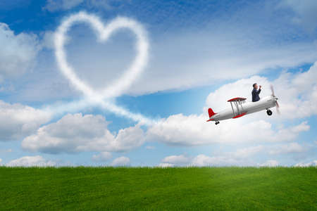 Man flying airplane and making heart shapeの写真素材