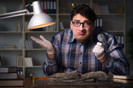 Archeologist working late night in officeの写真素材