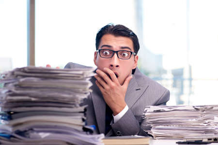 Busy angry businessman with heaps of paperの写真素材