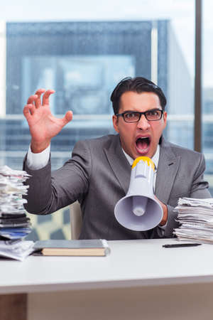 Angry businessman with loudspeaker in the officeの写真素材