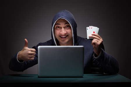 Young man wearing a hoodie sitting in front of a laptop computer