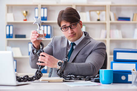 Businessman tied with chains to his workの写真素材