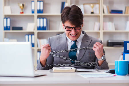 Businessman tied with chains to his workの写真素材