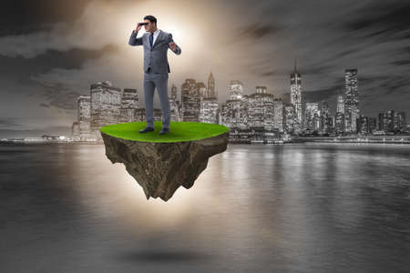 Businessman on flying island with binocularsの写真素材