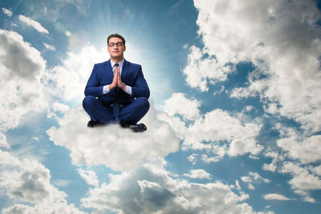 Businessman meditating in the sky
