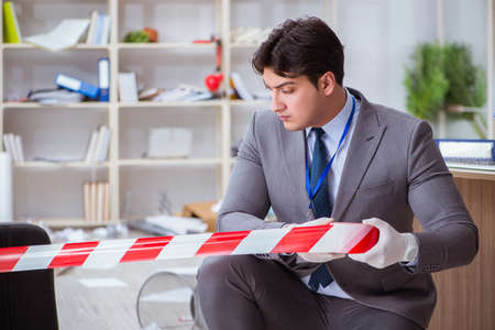 Young man during crime investigation in officeの写真素材