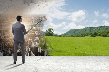 Businessman painting nature picture with roller brushの写真素材