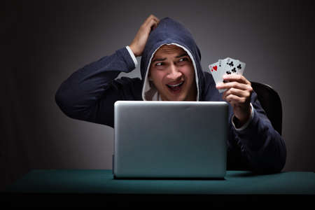 Young man wearing a hoodie sitting in front of a laptop computerの写真素材