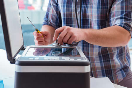 Repairman repairing broken color printerの写真素材