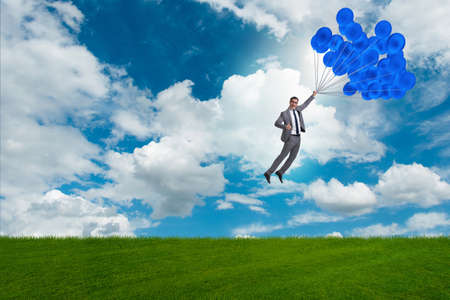 Businessman flying balloons on bright dayの写真素材