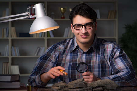 Archeologist working late night in officeの写真素材