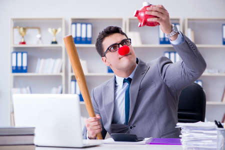 Clown businessman with a baseball bat and a piggy bankの写真素材