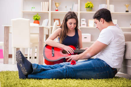 Romantic pair playing guitar on floorの写真素材