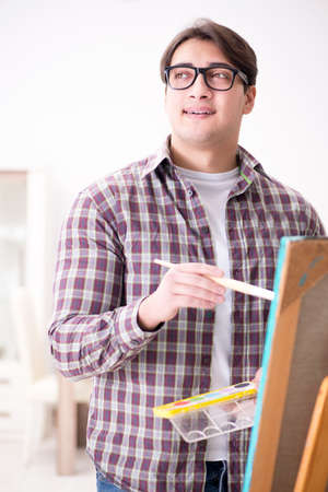 Young male artist drawing pictures in bright studioの写真素材