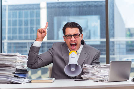 Angry businessman with loudspeaker in the officeの写真素材