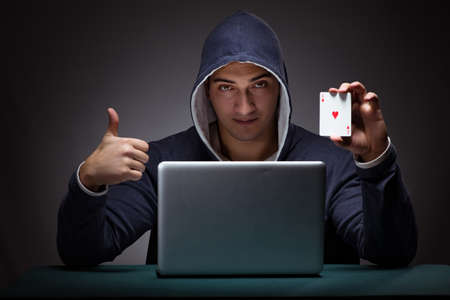Young man wearing a hoodie sitting in front of a laptop computerの写真素材