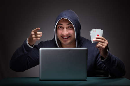 Young man wearing a hoodie sitting in front of a laptop computerの写真素材