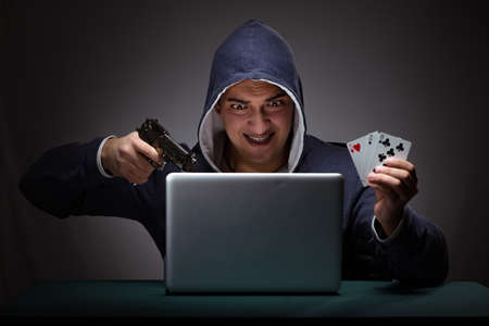 Young man wearing a hoodie sitting in front of a laptop computer