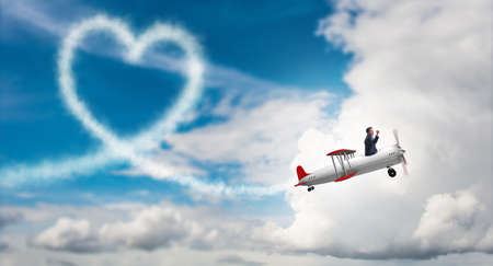 Man flying airplane and making heart shapeの写真素材