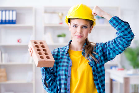 Woman with brick in construction concept