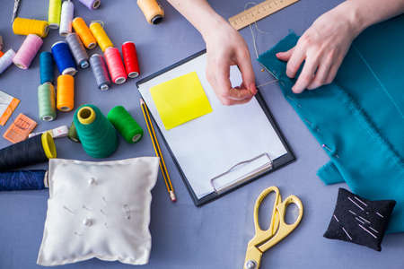 Woman tailor working on a clothing sewing stitching measuring fabricの写真素材