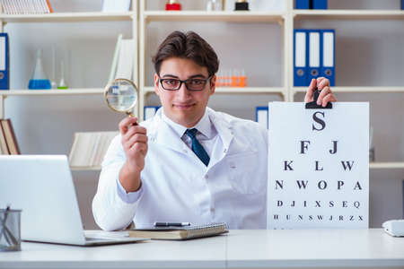 Doctor optician with letter chart conducting an eye test checkの写真素材