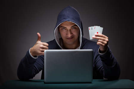 Young man wearing a hoodie sitting in front of a laptop computer