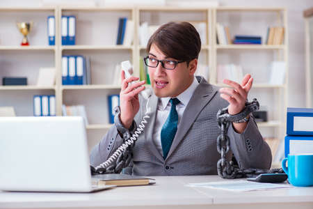 Businessman tied with chains to his workの写真素材