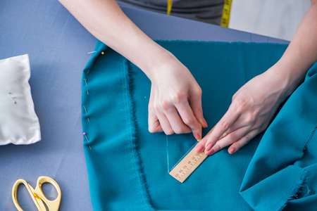 Woman tailor working on a clothing sewing stitching measuring fa
