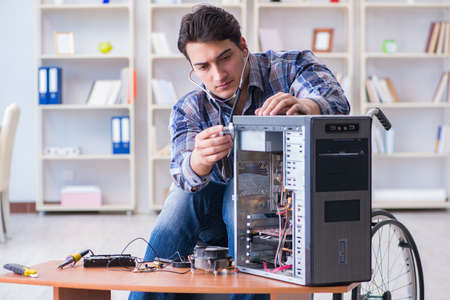 Disabled man on wheelchair repairing computerの写真素材